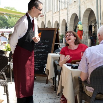 Serveur devant un couple attablé en terrasse d'un restaurant