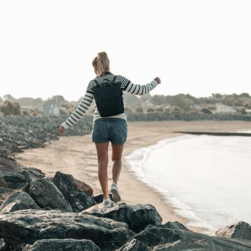 Jeune femme marchant sur des rochers le long de la plage
